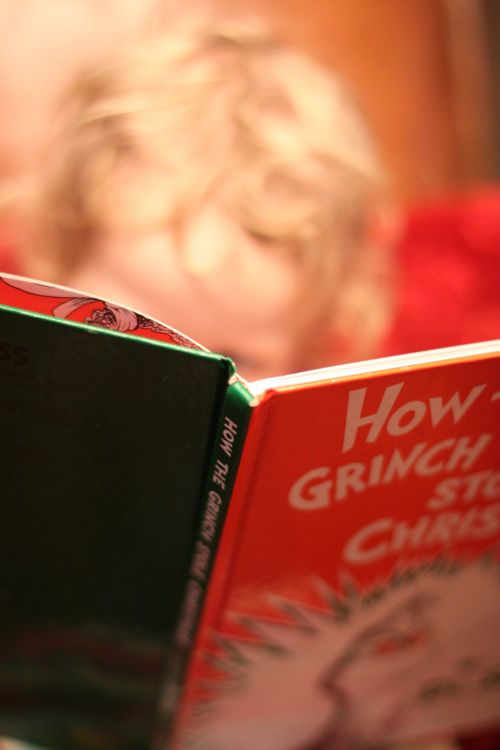 The Best Christmas Books featured by top US lifestyle blog, Design Mom: image of a child reading How to Grinch Stole Christmas